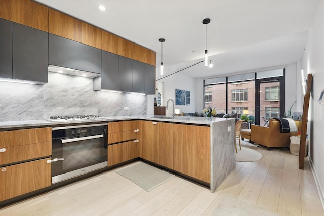 kitchen with decorative light fixtures, light hardwood / wood-style floors, backsplash, wall oven, and gas stovetop