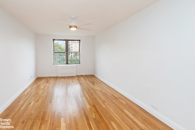 spare room featuring ceiling fan, light wood finished floors, and baseboards