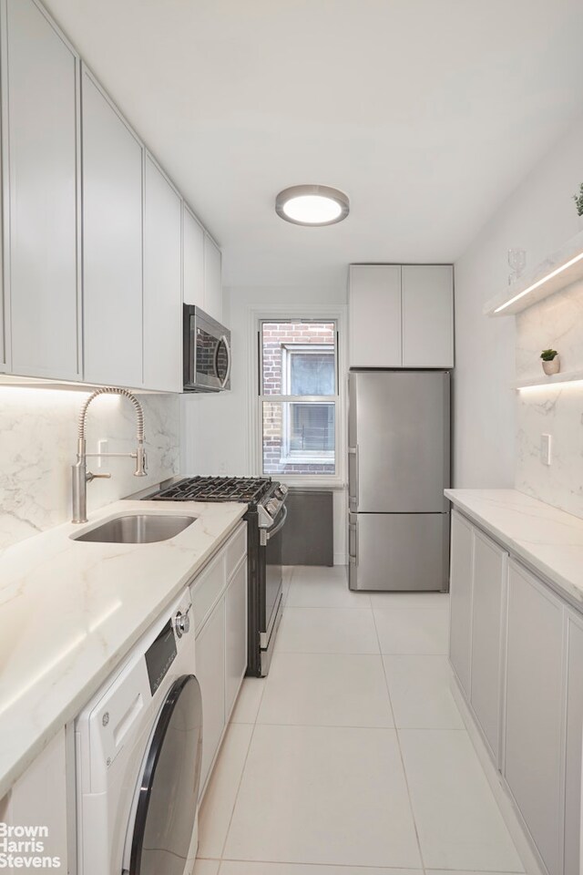 kitchen featuring appliances with stainless steel finishes, washer / clothes dryer, a sink, and tasteful backsplash