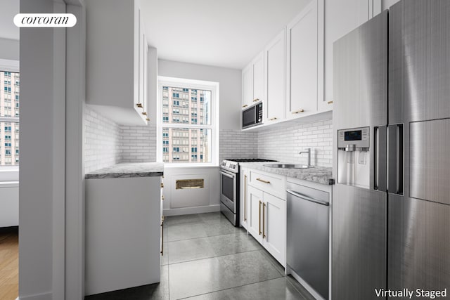 kitchen with light stone counters, plenty of natural light, appliances with stainless steel finishes, and white cabinets