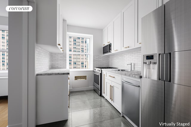 205 E 63rd St Unit 14D, New York City, NY 10065 - kitchen featuring appliances with stainless steel finishes, decorative backsplash, white cabinets, and light stone counters