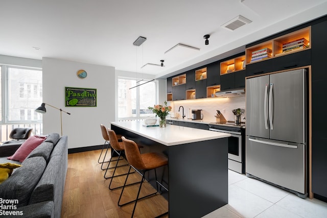 kitchen with pendant lighting, a breakfast bar, stainless steel appliances, a center island, and a healthy amount of sunlight