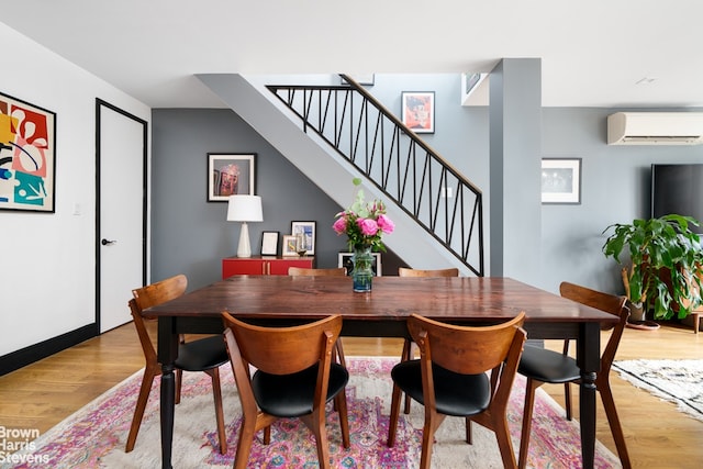 dining space featuring light hardwood / wood-style floors and an AC wall unit