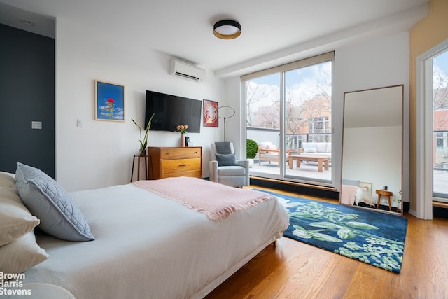 bedroom featuring multiple windows, hardwood / wood-style floors, and a wall unit AC