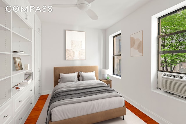 bedroom featuring baseboards, wood finished floors, ceiling fan, and cooling unit