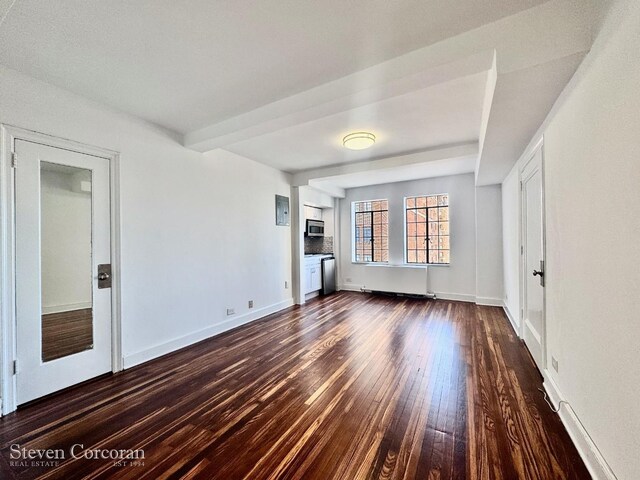 unfurnished living room with beamed ceiling and dark wood-type flooring