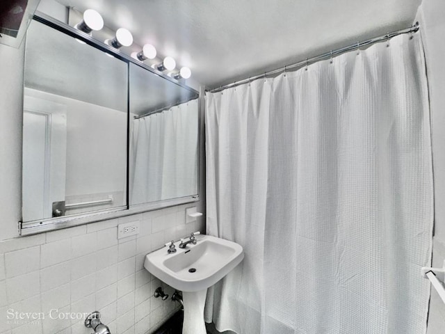 bathroom with tile walls, a shower with curtain, and tasteful backsplash