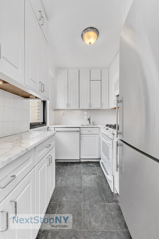 kitchen featuring light stone counters, white appliances, and white cabinets