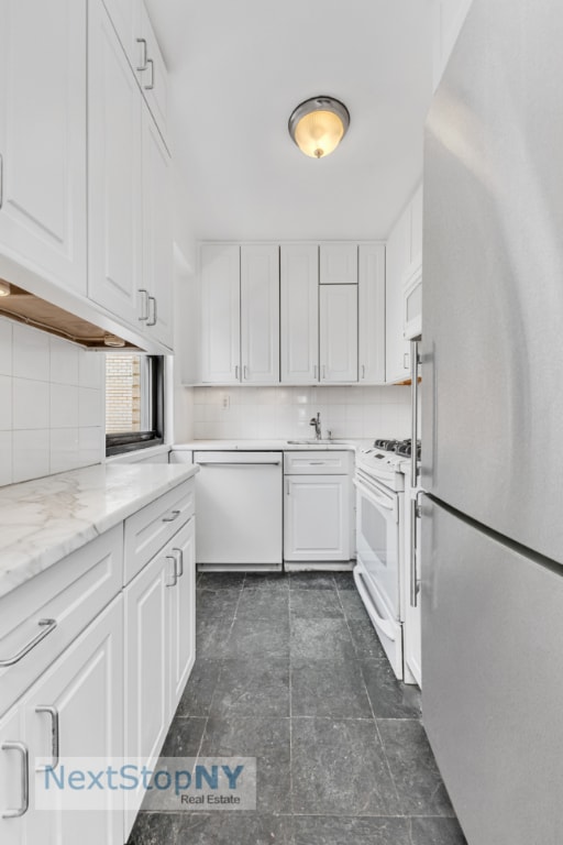 kitchen featuring backsplash, white appliances, and white cabinets