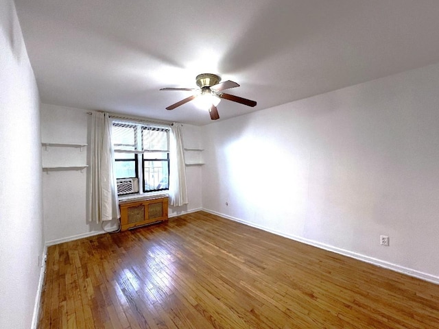 spare room featuring wood-type flooring, radiator heating unit, and ceiling fan