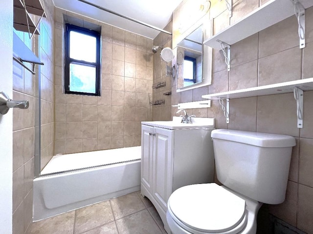 full bathroom featuring tile walls, tiled shower / bath, vanity, and toilet