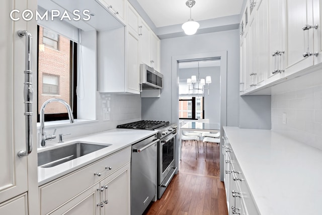 440 E 56th St Unit 8C, New York City, NY 10022 - kitchen with stainless steel appliances, dark wood-style floors, white cabinetry, backsplash, and light countertops