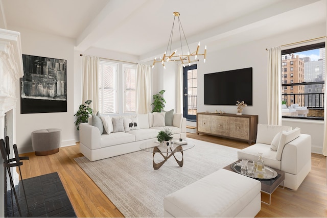 living room with beam ceiling, plenty of natural light, wood finished floors, and a chandelier