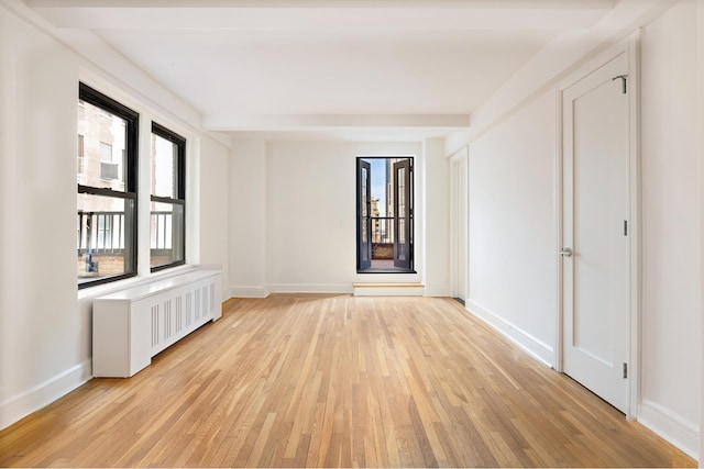 empty room with light wood-type flooring, radiator, and baseboards