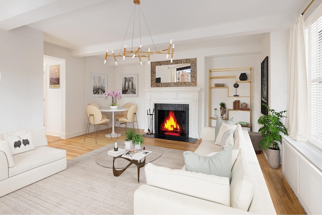 living room featuring wood finished floors, a lit fireplace, a chandelier, beamed ceiling, and baseboards