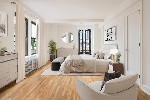 bedroom with light wood-style flooring, multiple windows, radiator heating unit, and a chandelier