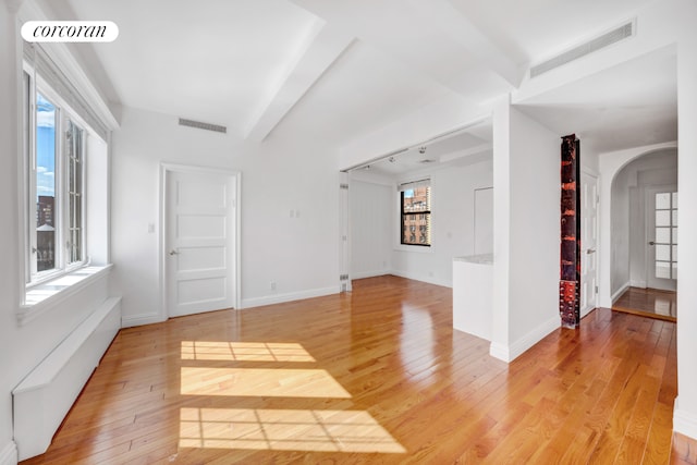 spare room with light hardwood / wood-style floors and beamed ceiling