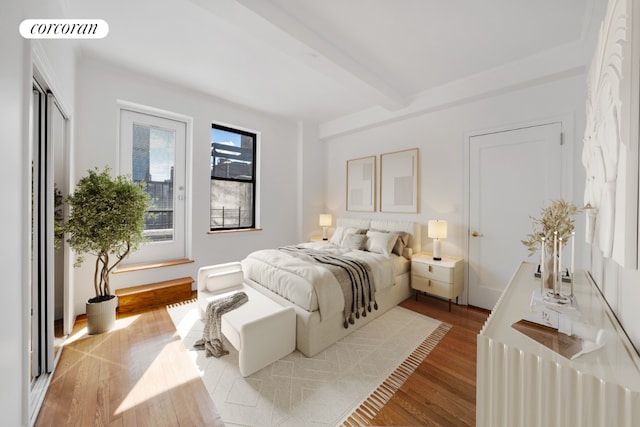 bedroom featuring beam ceiling and light hardwood / wood-style flooring