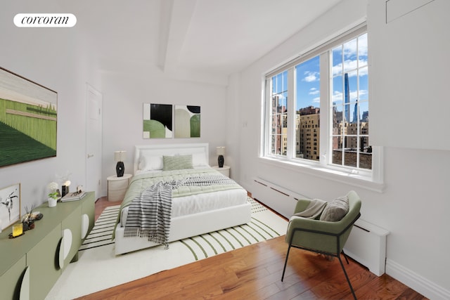 bedroom with a baseboard heating unit and wood-type flooring