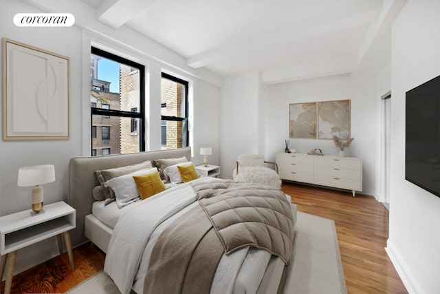 bedroom with beamed ceiling and light wood-type flooring