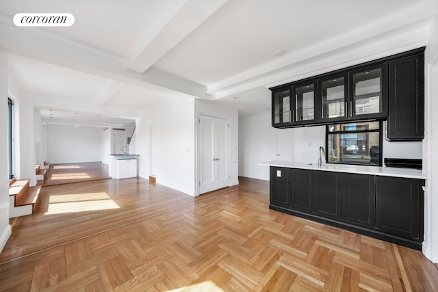 kitchen featuring beam ceiling, light parquet flooring, sink, and oven