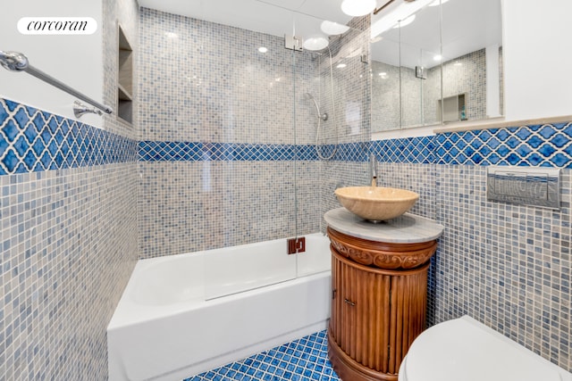 full bathroom featuring toilet, vanity, tile walls, tile patterned floors, and tiled shower / bath combo