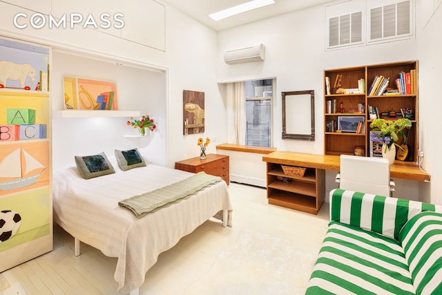 bedroom featuring a towering ceiling, wood finished floors, a wall unit AC, and built in desk