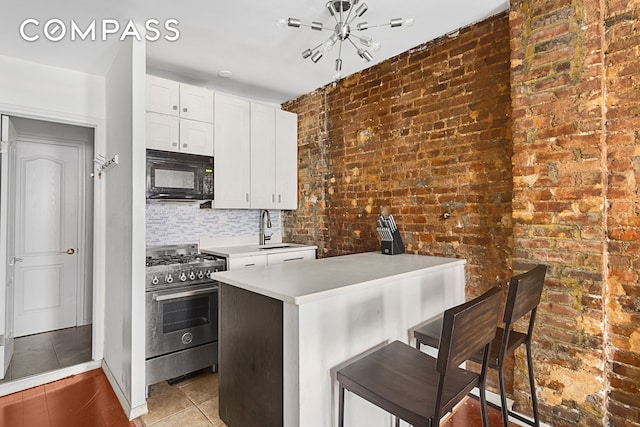 kitchen featuring stainless steel gas stove, brick wall, black microwave, a sink, and light tile patterned flooring