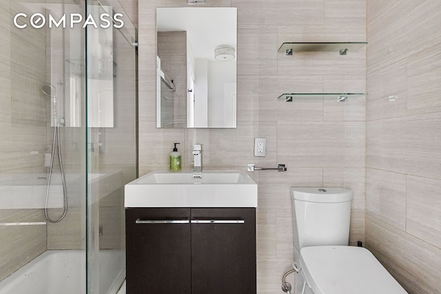 full bathroom featuring toilet, tile walls, vanity, and  shower combination