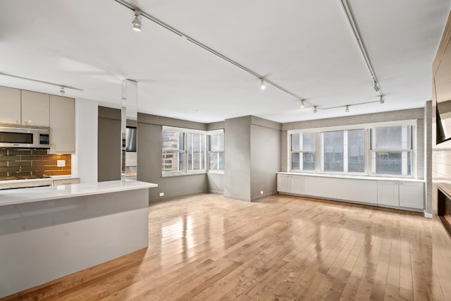 unfurnished living room with track lighting and light hardwood / wood-style flooring