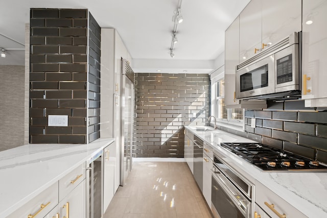 kitchen featuring stainless steel appliances, wine cooler, white cabinets, and light stone counters