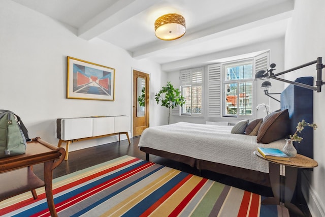 bedroom with beamed ceiling and wood finished floors