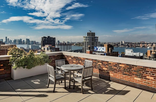 view of patio with a view of city, outdoor dining space, and a water view