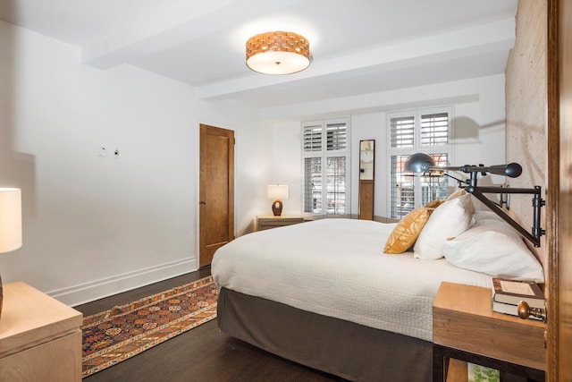 bedroom with dark wood finished floors, beamed ceiling, and baseboards