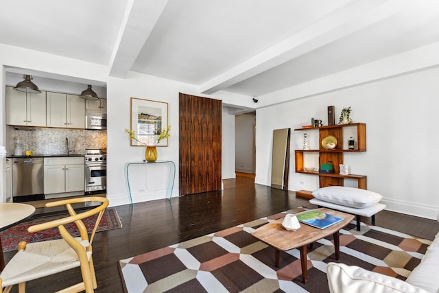 living area with beamed ceiling, baseboards, and wood finished floors