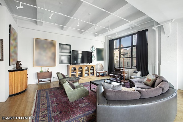 living area with rail lighting, wood finished floors, and beamed ceiling