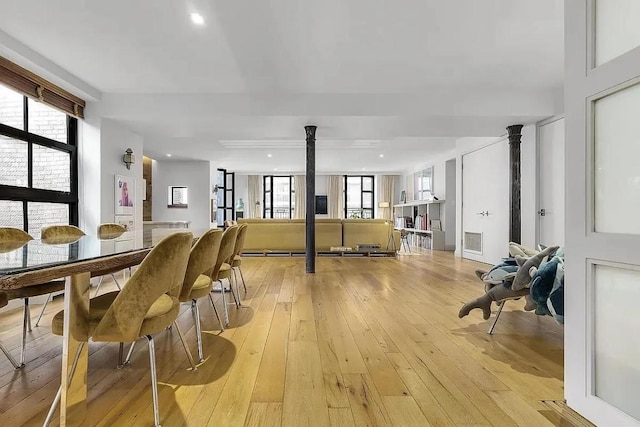 dining area with decorative columns, plenty of natural light, and light hardwood / wood-style flooring