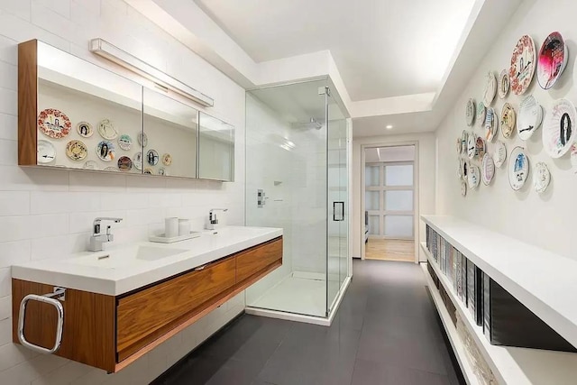 bathroom featuring tasteful backsplash, vanity, a shower with shower door, and tile walls