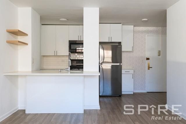 kitchen featuring open shelves, light countertops, freestanding refrigerator, white cabinetry, and a peninsula