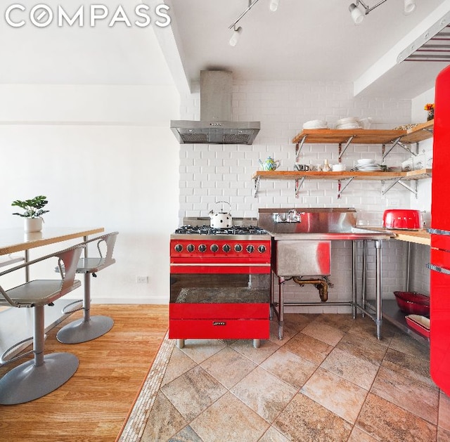 kitchen with decorative backsplash, sink, wall chimney exhaust hood, and stove