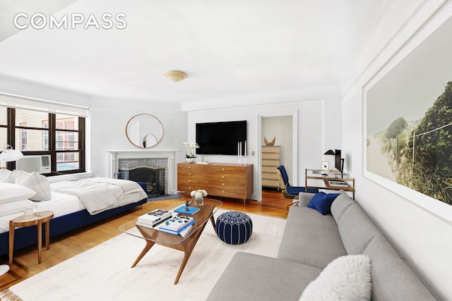 living area featuring a fireplace with raised hearth, wood finished floors, and cooling unit