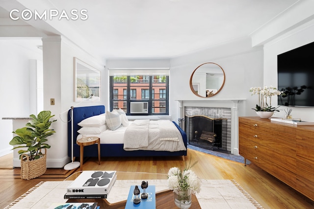 bedroom featuring a fireplace with raised hearth and wood finished floors