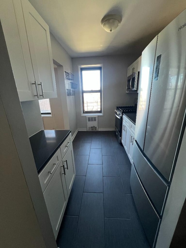 kitchen with dark countertops, white cabinets, baseboards, and appliances with stainless steel finishes