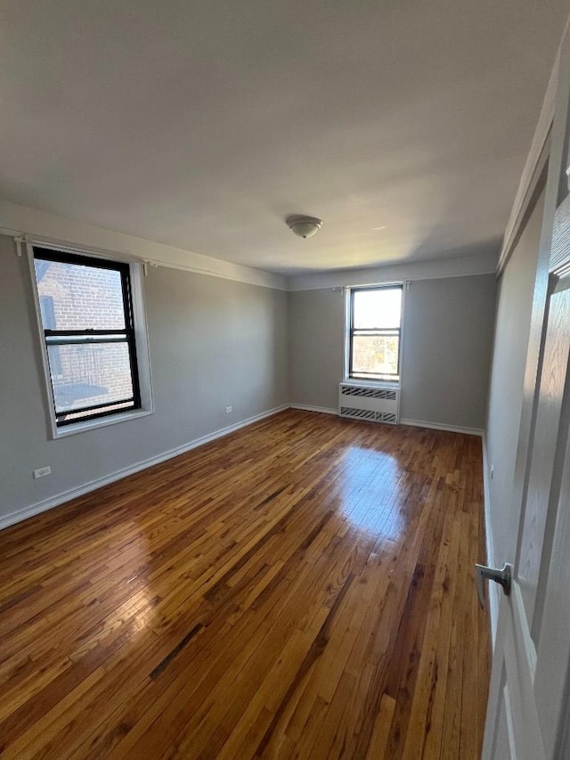 unfurnished room with radiator, baseboards, and hardwood / wood-style floors