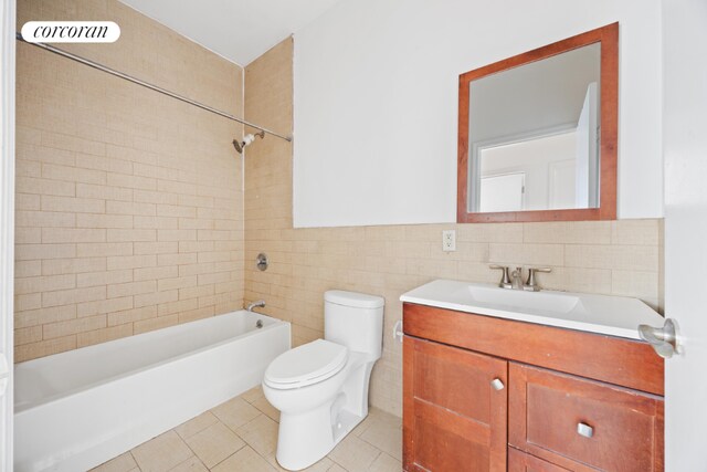 full bathroom featuring toilet, vanity, tile walls, tile patterned floors, and tiled shower / bath combo