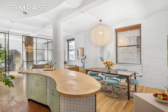 dining space with hardwood / wood-style flooring and brick wall