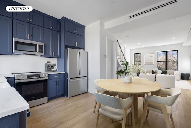 kitchen with backsplash, light hardwood / wood-style flooring, light stone countertops, appliances with stainless steel finishes, and blue cabinetry