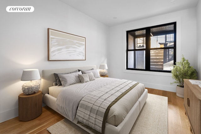 bedroom with wood finished floors, visible vents, and baseboards