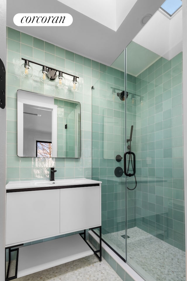 full bathroom featuring a stall shower, vanity, and tile walls