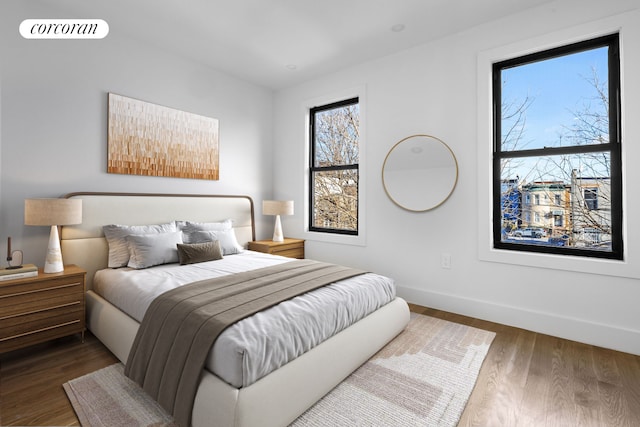 bedroom with wood finished floors, visible vents, and baseboards